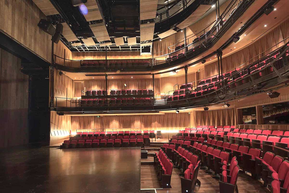 Interior of Wild Rice's Ngee Ann Kongsi Theatre in Singapore, showing the stage and tiered red seating.